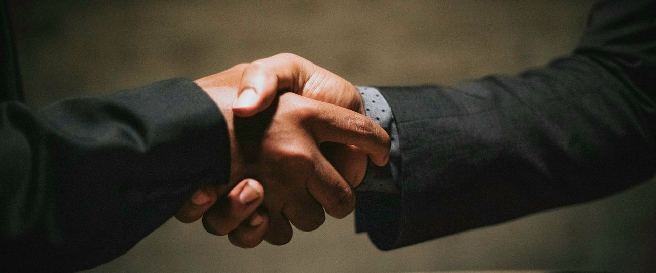 Two people shaking hands over a wooden table