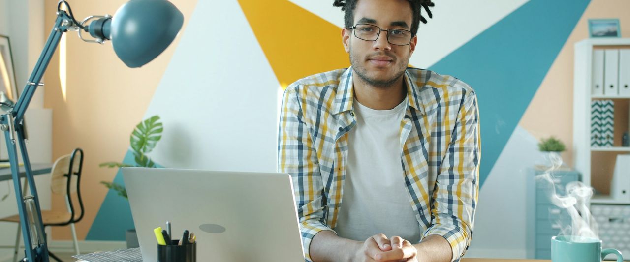 A business owner at a desk with a laptop and a steaming mug of coffee